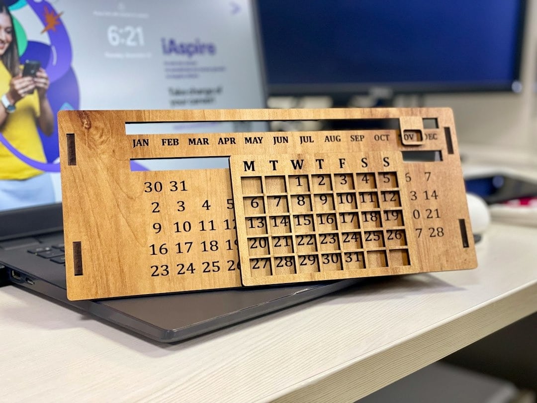 Mano che tiene un telefono con una calcolatrice vicino a dati finanziari su monitor.